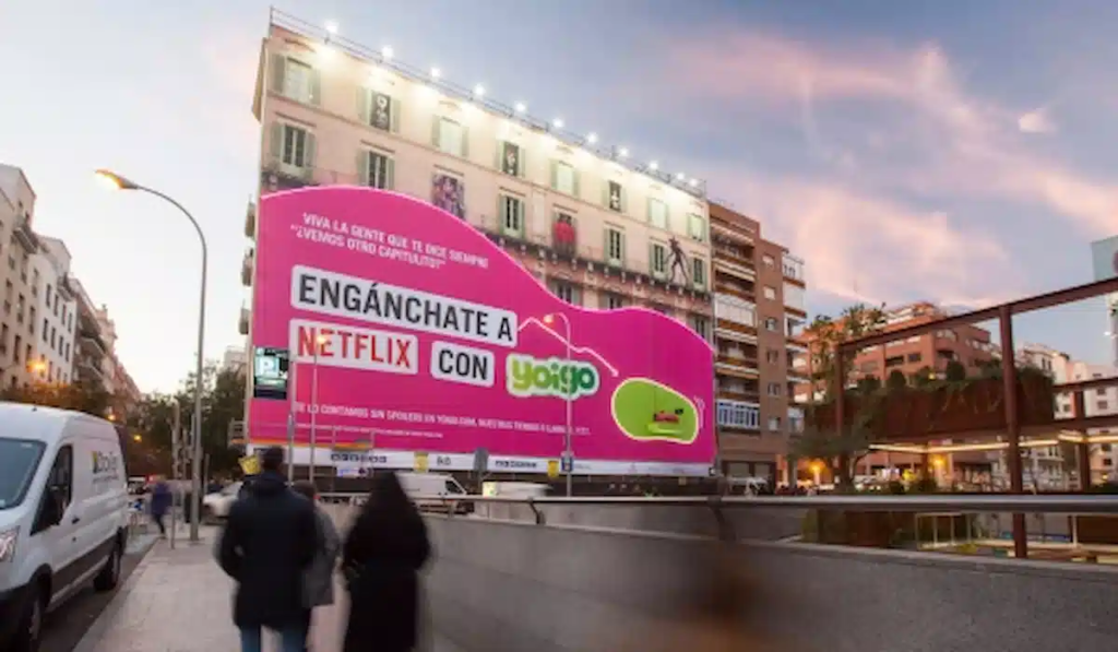 Yoigo billboard with influencer watching Netflix on a sofa suspended 24 metres above Madrid street