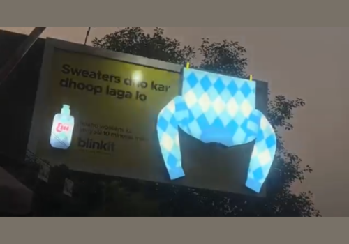 Blinkit yellow sweater-shaped billboard with soft sunlight effect lit up at night